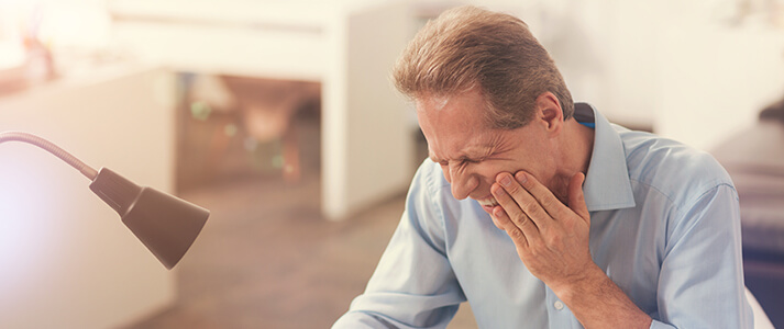 Older man experiencing tooth pain while in his office
