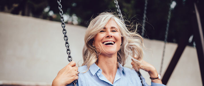 Older woman swinging on swing with new dentures
