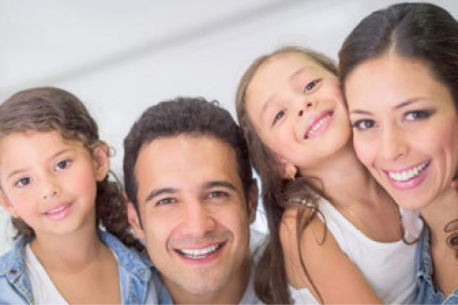 young family of four smile at the camera
