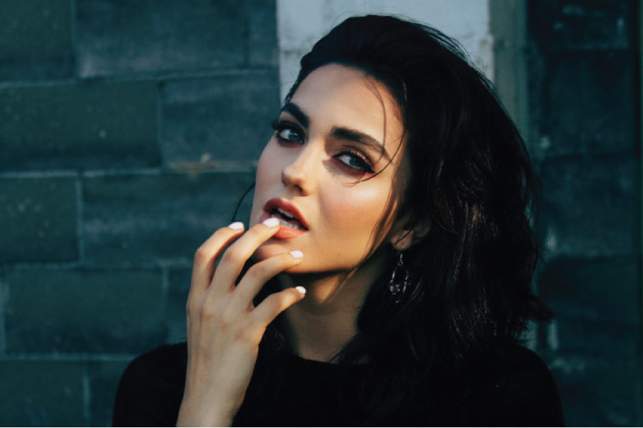 young dark haired woman holds her lower lip with an irritated bump on her gums