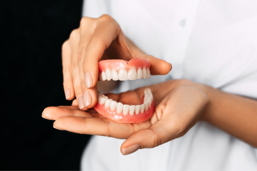 pair of hands holding a pair of dentures